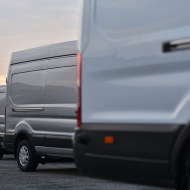 Several vans parked up in row with sun setting behind